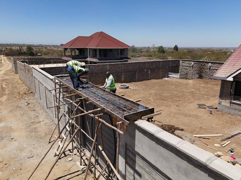 Stone boundary wall under construction with site machinery