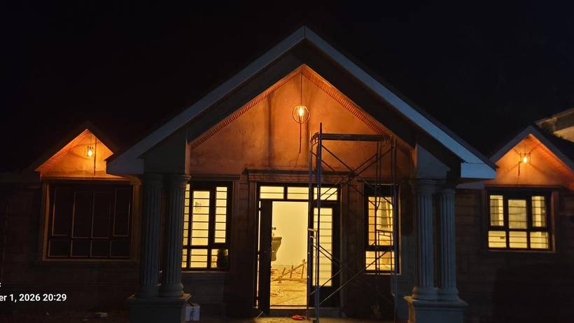 Completed residence lit at night showing pillars and gables